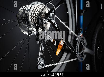 Roue arrière de bicyclette, levier de vitesses, cassette de pignon et chaîne. Vue arrière sur fond noir. Banque D'Images