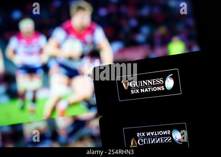 Un smartphone affichant le logo Guinness six Nations Championship avec un match de rugby flou en arrière-plan. Banque D'Images