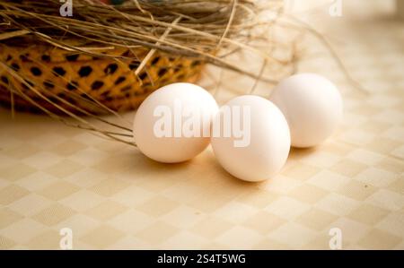 Photo gros plan de trois œufs blancs se trouvant sur la table à côté de panier Banque D'Images
