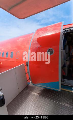 Photo de porte ouverte de gros avion civil peint en rouge Banque D'Images