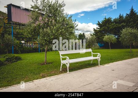 Belle vue sur banc blanc en parc avec arbres et pelouse Banque D'Images