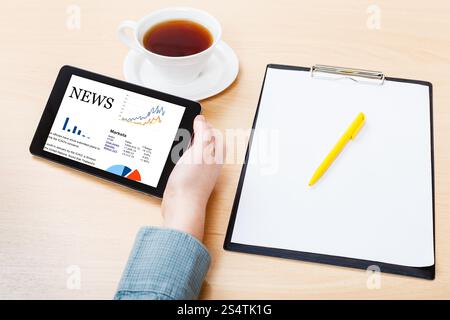 Businessman hand avec Tablet PC avec business news sur écran à la table office Banque D'Images