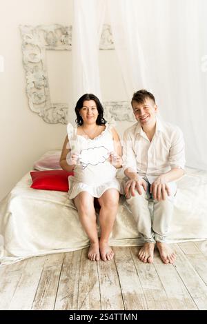 Photo de tons happy pregnant woman sitting on bed with copy space signe papier Banque D'Images