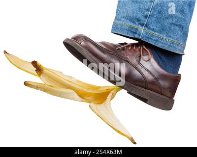 Jambe gauche mâle en jeans et Brown Shoe glisse sur une peau de banane isolé sur fond blanc Banque D'Images