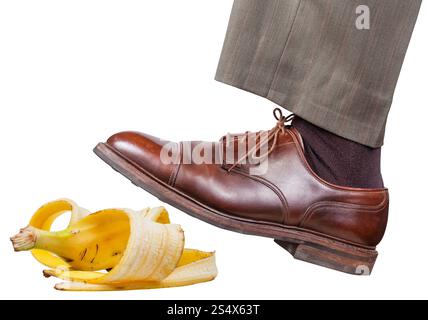 Dans la partie gauche de la jambe mâle brown shoe glisse sur une peau de banane isolé sur fond blanc Banque D'Images
