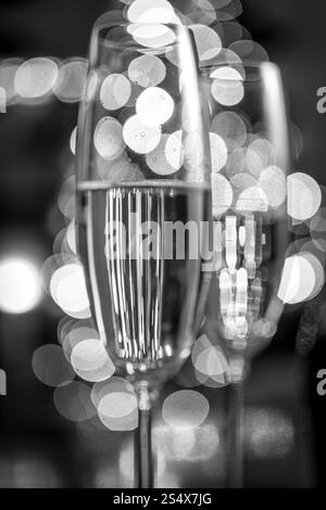 Macro photo en noir et blanc de deux verres de champagne sur fond de lumières de Noël Banque D'Images