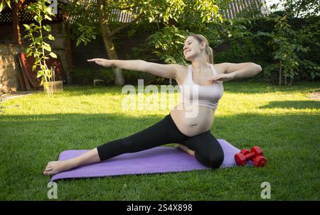 Jeune femme enceinte s'étend au parc en journée ensoleillée Banque D'Images