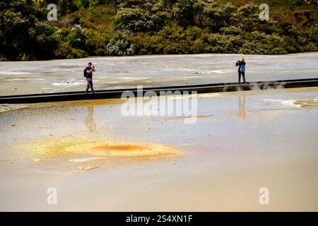 Visiteurs marchant sur la promenade traversant Champagne Pool à Wai-O-Tapu Thermal Wonderland, Rotorua, Nouvelle-Zélande, Nouvelle-Zélande, Nouvelle-Zélande, Nouvelle-Zélande, explorant les piscines géothermiques colorées. Banque D'Images