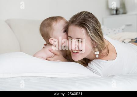 Portrait of happy laughing woman with her baby boy on bed Banque D'Images