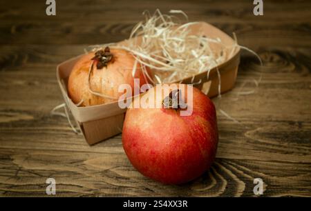 Photo gros plan de deux grenades couché dans le panier sur le vieux bureau en bois Banque D'Images