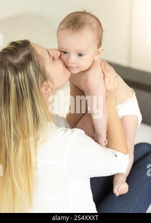 Portrait of happy young mother holding her baby son et en l'embrassant dans la joue Banque D'Images