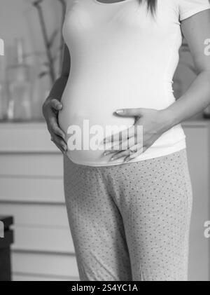 Noir et blanc belle femme enceinte en t-shirt blanc touchant le gros ventre Banque D'Images