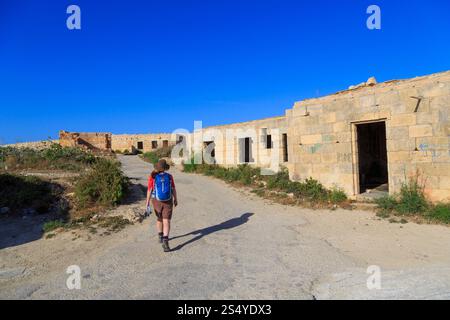 Randonneur marchant devant des bâtiments en ruines dans le nord de Malte Banque D'Images