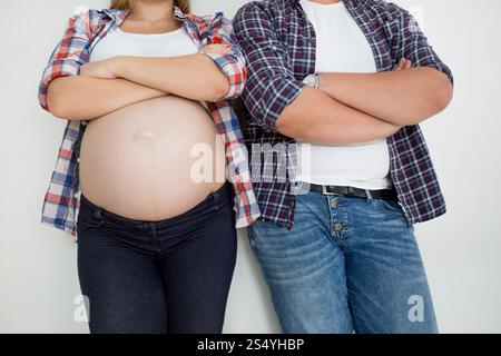 Gros plan photo d'une femme enceinte et d'un mari appuyés sur un mur blanc Banque D'Images