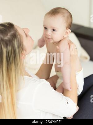 Heureuse jeune mère tenant son fils bébé et l'embrassant dans la joue Banque D'Images