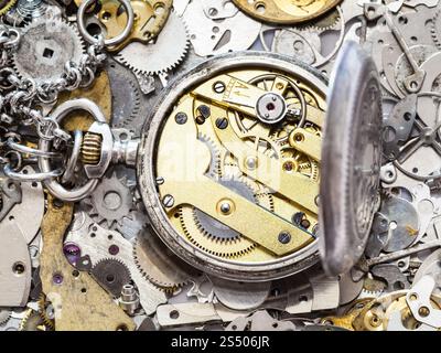 Atelier horloger - open old silver montre de poche avec une horloge en laiton sur le tas de pièces de rechange de l'horloge Banque D'Images