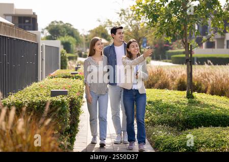 Heureux jeune couple latin et agent immobilier regardant bien quartier de banlieue Banque D'Images