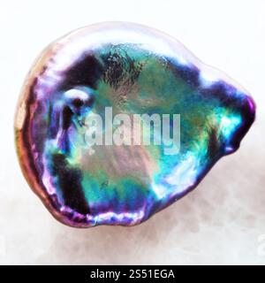 La prise de vue macro des eaux minérales naturelles rock specimen - tumbled ormeau Haliotis) pierre sur fond de marbre blanc Banque D'Images