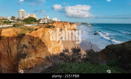 Magnifique coucher de soleil sur la côte à Portimão, Portugal, avec le soleil qui brille sur les falaises supérieures et la plage vue de la mer Banque D'Images