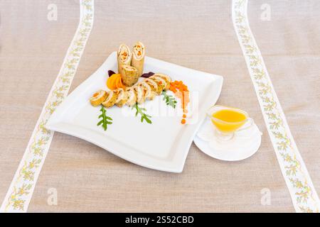 Un plateau de fruits de mer gastronomique magnifiquement arrangé avec des fruits de mer roulés avec des garnitures colorées. Le plat est servi sur une assiette blanche, en soulignant son Banque D'Images