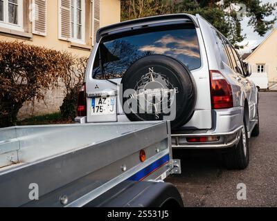 Paris, France - 10 mars 2019 : vue arrière d'un SUV Mitsubishi Pajero argenté tractant une remorque métallique, garé dans un quartier résidentiel avec une maison beige et Banque D'Images