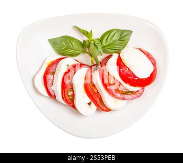 cuisine italienne insalata caprese (salade caprese) - vue de dessus de fromage mozzarella tranché et tomate avec brindilles de basilic assaisonnées d'huile d'olive sur l'assiette Banque D'Images