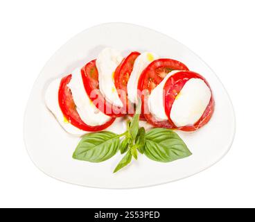 cuisine italienne insalata caprese (salade caprese) - vue de dessus de fromage mozzarella tranché et tomate avec brindille de basilic sur assiette isolé sur blanc Banque D'Images