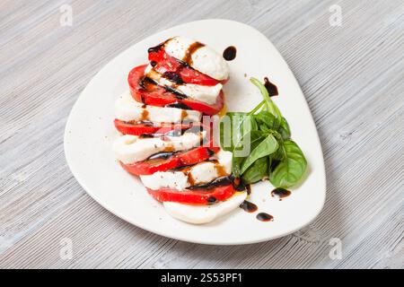 cuisine italienne insalata caprese (salade caprese) - tranches de fromage mozzarella et tomate avec brindilles de basilic assaisonnées d'huile d'olive et de vinaigre balsamique Banque D'Images
