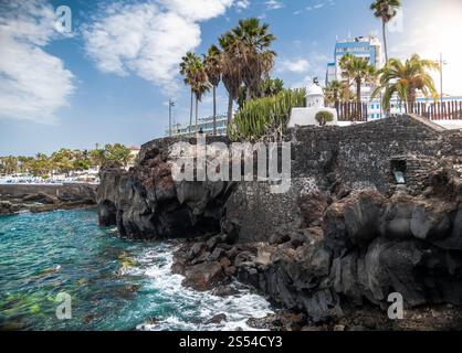 Photo étonnante sur des palmiers verts et un bâtiment moderne au sommet de hautes falaises volcaniques à la lagune océanique. Vue imprenable sur des palmiers verdoyants et moderne Banque D'Images