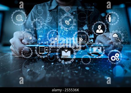 E-learning avec engrenages connectés diagramme connecté tableau de bord virtuel.main d'homme d'affaires travaillant avec la technologie moderne tablette numérique et Banque D'Images