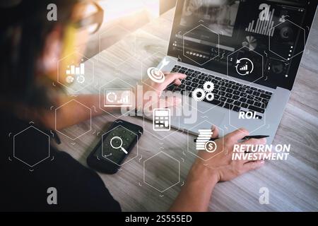 Indicateur de retour sur investissement sur investissement dans le tableau de bord virtuel pour améliorer l'activité. main de designer assistant à la vidéoconférence avec ordinateur portable et Banque D'Images