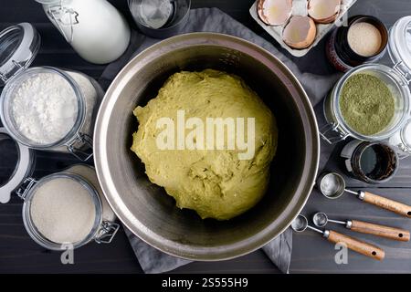 Pâte à pain Matcha verte dans un bol à mélanger : Unrisen thé vert Babka pâte dans un bol à mélanger entourée d'autres ingrédients de pain et d'outils de cuisine Banque D'Images