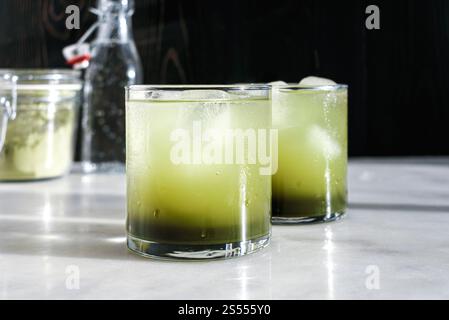 Deux verres de Matca Soda avec glaçons : eau pétillante mélangée à du sirop simple matcha servi dans des verres de roches Banque D'Images