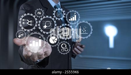 Gestion de l'analyse des données d'entreprise avec engrenages connectés avec graphiques et graphiques financiers KPI. Main d'homme d'affaires travaillant avec une tablette numérique sur Banque D'Images