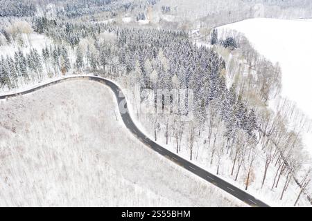 Vue aérienne d'une route de campagne sinueuse et forêt dans la neige, entre Eppendorf et Leubsdorf, Saxe central, Allemagne, Europe Banque D'Images