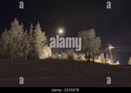 Pleine lune sur la piste de ski enneigée avec téléphérique à Eibenstock la nuit, Erzgebirge, Saxe, Allemagne, Europe Banque D'Images
