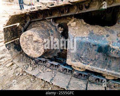 Gros plan photo de chenilles de pelle couvertes de terre sur le chantier de construction. Gros plan des chenilles de pelle couvertes de terre sur le chantier de construction Banque D'Images