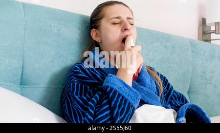 Portrait d'une femme malade atteinte de grippe en utilisant le spray Thpat. Portrait d'une femme malade atteinte de grippe en utilisant le spray Thpat Banque D'Images