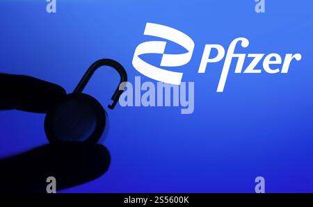 Une main tient un cadenas déverrouillé devant le logo pfizer. Pfizer Inc. est une multinationale américaine pharmaceutique et biotechnologique Banque D'Images