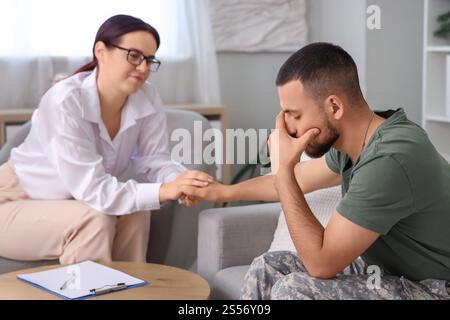 Soldat contrarié avec le TSPT et psychologue tenant la main au bureau Banque D'Images