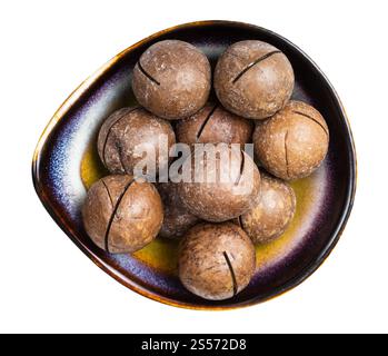 vue de dessus des noix de macadamia sciées dans un bol en céramique isolé sur fond blanc Banque D'Images