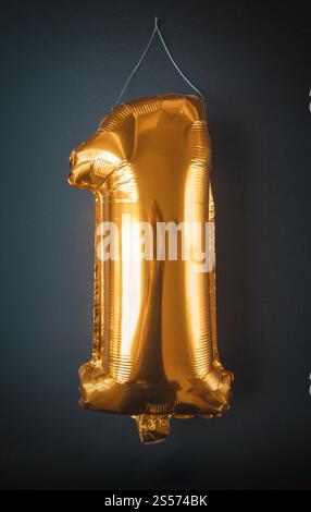Feuille d'or ballon numéro un isolé sur fond noir. Feuille d'or ballon numéro un isolé sur noir Banque D'Images
