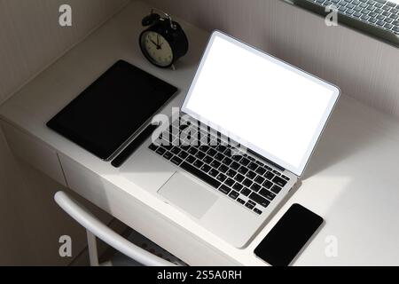 Écran blanc ordinateur portable et téléphone intelligent et tablette numérique et stylo sur le bureau en bois en tant que concept de poste de travail Banque D'Images