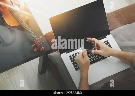 Hipster part composer de la musique avec ordinateur portable compter et tenant une tasse de café et sitting on sofa at home studio Banque D'Images