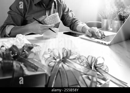 Cadeau donnant main créative choix et main avec cadeau. Livraison de cadeau, surprise, ordinateur latop et téléphone intelligent sur le bureau mable, noir blanc Banque D'Images