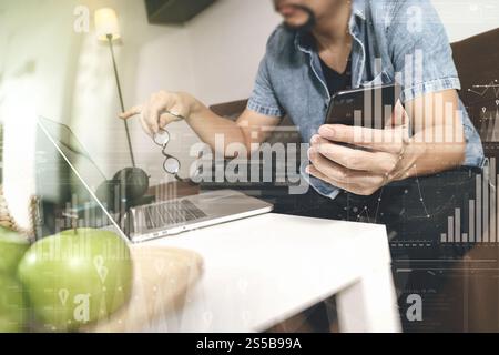 main hipster utilisant le compte d'ordinateur portable et les paiements mobiles en ligne affaires, lunettes, assis sur le canapé dans le salon, pommes vertes dans le plateau en bois, graphique Banque D'Images