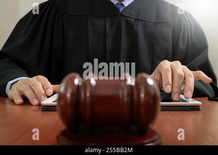 La justice et du droit concept.Homme juge dans une salle d'audience le marteau frappe,travailler avec station d'ordinateur tablette numérique sur clavier table bois Banque D'Images