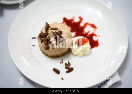 Gros plan d'un dessert à la crème glacée au chocolat avec crème fouettée et sauce coulis de fruits Banque D'Images