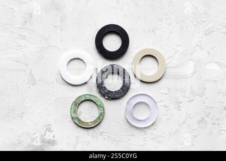 vue de dessus des différents joints pour la tuyauterie des systèmes d'eau sur fond en béton gris (caoutchouc, caoutchouc sous vide, silicone, ptfe, paronite) Banque D'Images