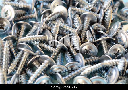 Beaucoup de petites vis argentées sont dans un gros tas chaotique. Vue macro gros plan. Beaucoup de petites vis argentées sont dans un gros tas chaotique Banque D'Images